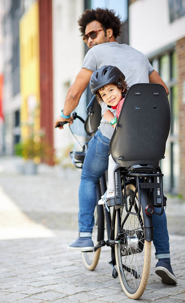 Een vader en zijn kind zitten op een fiets met Urban Iki achterzitje